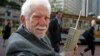 Martin Cooper, pictured here in 2003, holds the original model of the protype phone he used to make the first ever cell phone call in 1973.