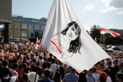 People hold a flag with a portrait of Sviatlana Tsikhanouskaya, main opposition candidate in Belarus' presidential elections, during a rally in Minsk, Belarus, Aug. 17, 2020.