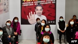 Warga berpartisipasi dalam latihan pencegahan wabah virus corona menunggu di depan poster Wali Kota New Taipei Citi Hou You-yi, di distrik Xindian, 14 Maret 2020. (Foto: AFP)