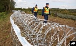 FILE - Hungarian police officers patrol an area at the temporary border fence positioned at the green border between Hungary and Croatia at Zakany, 234 km (145 miles) southwest of Budapest, Hungary, Sept. 30, 2015.