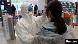 2020年1月24日农历新年前夕，穿着防护服的工作人员检查（到达与武汉北部接壤的）咸宁市乘客的体温。