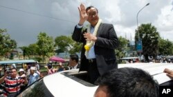 FILE - In this Aug. 16, 2015, file photo, Sam Rainsy, leader of the opposition Cambodia National Rescue Party (CNRP), waves from a car upon his arrival at Phnom Penh International Airport in Phnom Penh, Cambodia as hundreds of cheering supporters greeted him on his return from a trip abroad. The head of Cambodia's opposition party has announced his resignation from the group after the country's long-serving prime minister announced plans for a law that could lead to the party's dissolution. Rainsy announced his resignation Saturday, Feb. 11, 2017, in a letter to his Cambodia National Rescue Party. (AP Photo/Heng Sinith)