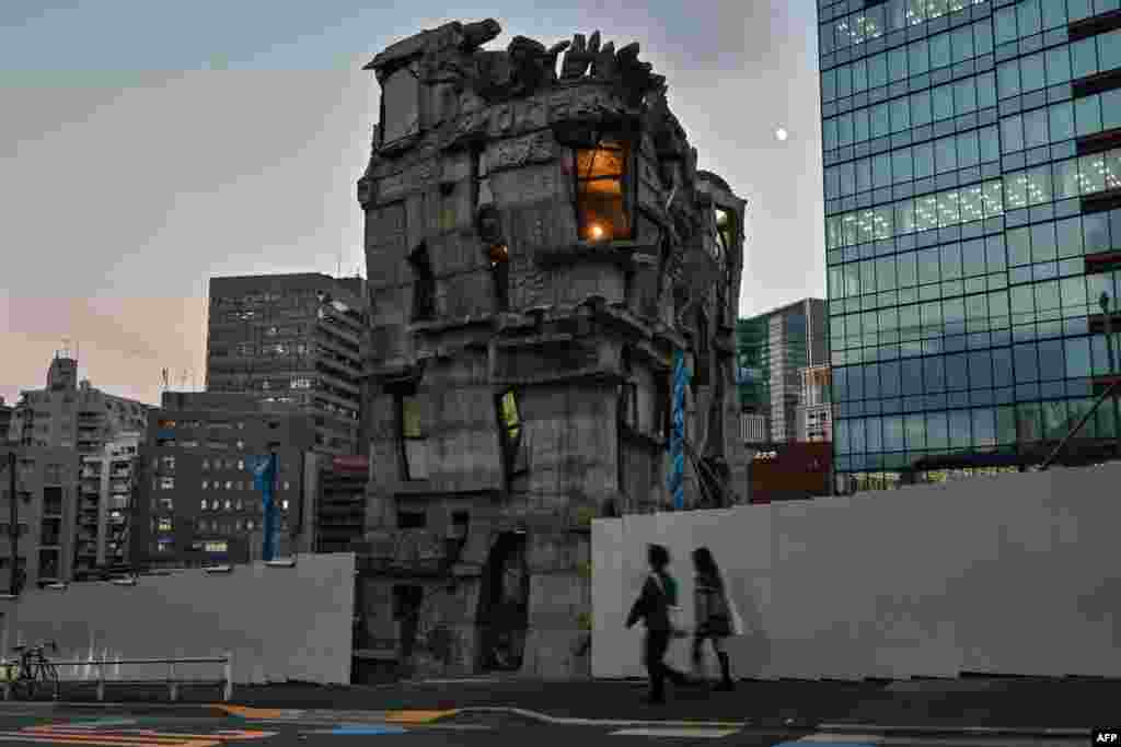 This photo taken on Nov. 13, 2024 shows pedestrians walking past the four-storey Arimaston Building by Japanese architect Keisuke Oka in the Mita area of Minato Ward in Tokyo.&nbsp;Passers-by stop and stare at the ramshackle, hand-built concrete tower that looks like it has been lifted right out of a Japanese animation and dropped onto a real-life Tokyo street. Oka started construction in 2005. Apart from the help of a few friends, he made the entire building himself by hand.&nbsp;
