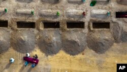 Funeral workers carry a coffin containing the body of an unidentified civilian who died in the Bucha community territory during the Russian occupation period in February-March 2022, during a funeral in Bucha, near Kyiv, Ukraine, Sept. 2, 2022. 