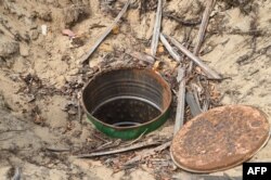 FILE - A deep hole dug by vandals to steal oil from pipelines belonging to the Nigerian National Petroleum Company (NNPC) are pictured near Tarkwa Bay waterfront settlement in Lagos, on Jan. 23, 2020.