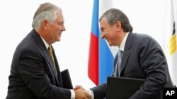 CEO Rosneft, perusahaan minyak berbasis Rusia (kanan), Igor Sechin berjabat tangan dengan CEO Exxon Mobil Corp. Rex Tillerson (sekarang menjabat sebagai Menlu AS), seusai penandatanganan kesepakatan di Pelabuhan Laut Hitam Tuapse, selatan Rusia, 15 JUni 2012. (AP Photo/RIA-Novosti, Mikhail Klimentyev, Presidential Press Service).