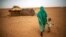 File photo released by the United Nations African Union Mission in Darfur (UNAMID), a woman holds hands with her daughter as they walk at the Zam Zam refugee camp for internally displaced people (IDP) in North Darfur, Sudan. 