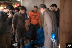 FILE - Residents carry the body of a person killed during fights between Iraq security forces and Islamic State on the western side of Mosul, Iraq, March 24, 2017.