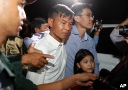 FILE - Two former Radio Free Asia reporters Uon Chhin, center, and Yeang Socheamet, right, hold together as they walk outside the main prison of Prey Sar at the outskirt of Phnom Penh, Cambodia, Aug. 21, 2018.