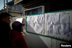 People look at a list of casualties near a burnt hospital in Miryang, South Korea, Jan. 26, 2018.