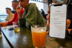 Seorang pelanggan di tempat pembuatan bir Denmark, Mikkeller's pub Warpigs, menunjukkan “Corona pass” mereka. (AFP)