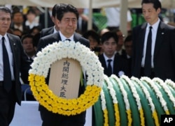 Japanese Prime Minister Shinzo Abe holds a wreath during a ceremony to mark the 70th anniversary of the Nagasaki atomic bombing in Nagasaki, southern Japan, Aug. 9, 2015.