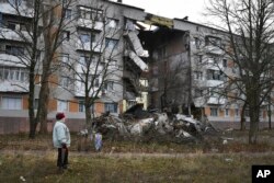 A woman passes by an apartment building damaged following by Russian shelling in Bakhmut, the site of the heaviest battles with the Russian troops, in the Donetsk region, Ukraine, Sunday, Dec. 11, 2022. (AP Photo/Andriy Andriyenko, File)