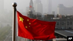 FILE - Bendera nasional China berkibar di depan gedung perkantoran di Shanghai, 14 April 2016. (AP/Andy Wong, File).