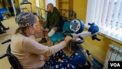 Andriy, 44, sitting in background, says he will return to the front lines when he is able to fully use his prosthetic leg, in Lviv, Ukraine, Jan. 16, 2023. (Yan Boechat/VOA)
