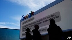 FILE - Workers set up a Google billboard at the Las Vegas Convention Center ahead of the CES technology show on January 2, 2023, in Las Vegas.
