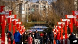 Visitors walk across a bridge decorated with lanterns at a public park in Beijing on the first day of the Lunar New Year holiday, Jan. 22, 2023.