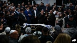 Mourners gather around the bodies of Israeli couple Eli Mizrahi and his wife, Natalie, victims of a shooting attack Friday in east Jerusalem, during their funeral at the cemetery in Beit Shemesh, Israel, Jan. 29, 2023. 