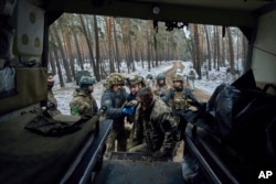 Military medics help a wounded soldier into an evacuation vehicle near Kremenna in the Luhansk region, Ukraine, Jan. 16, 2023.