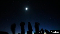 Cahaya bulan tampak bersinar di atas sekelompok orang yang tengah mengikuti tur UFO di Sedona, Arizona, pada 14 Februari 2013. (Foto: Reuters/Mike Blake)