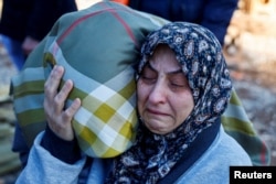 A woman reacts as people bury victims of the deadly earthquake, in a cemetery in Kahramanmaras, Turkey, Feb. 9, 2023.