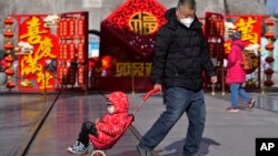 A man pulls a child past a Lunar New Year decoration on display at the Qianmen pedestrian shopping street, a popular tourist spot in Beijing, Jan. 17, 2023. (AP Photo/Andy Wong)