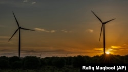 Matahari terbenam di balik turbin angin di distrik Anantapur, Andhra Pradesh, India, Rabu, 14 September 2022. (Foto: AP)