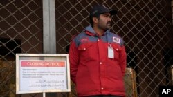 A worker of the Orange Line metro train stands next to a closing notice board at a station following a power breakdown across the country, in Lahore, Pakistan, Jan. 23, 2023.