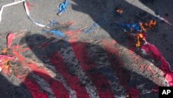 A representation of the U.S flag is set on fire by demonstrators during the annual rally commemorating Iran's 1979 Islamic Revolution, in Tehran, Iran, Feb. 11, 2023.
