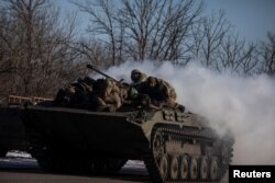 Ukrainian service members ride atop of a BMP-2 infantry fighting vehicle near a frontline in Donetsk region, Ukraine, Feb. 8, 2023.