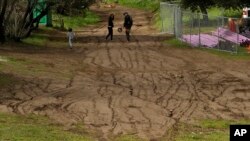 A family walks on a stretch of land eroded by rain flow in Elysian Park in Los Angeles, Jan. 19, 2017. California has been getting soaked with a series of heavy storms.
