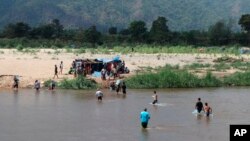 Displaced people from Myanmar wade across the river from Thailand into Myanmar, as seen from Mae Sot, Thailand, Feb. 7, 2022.