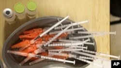 FILE - Medical personnel reach for pre-loaded syringes as they vaccinate students at KIPP Believe Charter School in New Orleans, Tuesday, Jan. 25, 2022. (AP Photo/Ted Jackson, File)