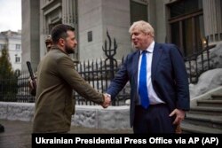 Presiden Ukraina Volodymyr Zelenskyy, kiri, dan Perdana Menteri Inggris Boris Johnson, berjabat tangan di pusat kota Kyiv, Ukraina, Sabtu, 9 April 2022. (Kantor Pers Kepresidenan Ukraina via AP)