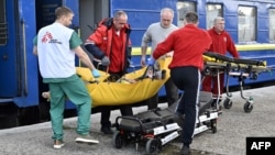 Ambulance workers and MSF medics transfer a patient from an evacuation train to an ambulance in the western Ukrainian city of Lviv, April 10, 2022.