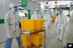 Pekerja medis mengenakan APD bergerak melalui Shanghai New International Expo Center, yang telah diubah menjadi fasilitas karantina untuk pasien COVID-19 dengan gejala ringan atau tanpa gejala, 1 April 2022. (Xinhua via AP)