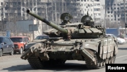 Tenk proruskih trupa vozi duž puta u blizini spaljenih stambenih zgrada u južnom lučkom gradu Mariupolju, Ukrajina, 5. aprila 2022. REUTERS/Alexander Ermochenko