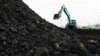 Seorang pekerja mengoperasikan kendaraan berat untuk menurunkan batu bara dari tongkang ke truk, di pelabuhan Karya Citra Nusantara di Jakarta Utara, 13 Januari 2022. (REUTERS/Willy Kurniawan)