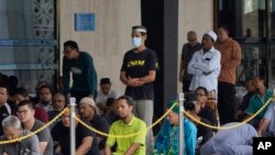 Malaysian Muslims attend Friday prayers with shorter sermons at the National Mosque in Kuala Lumpur, Malaysia, Friday, March 13, 2020. For most people, the new coronavirus causes only mild or moderate symptoms. (AP Photo/Vincent Thian)