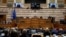 Ukrainian President Volodymyr Zelenskyy, on the screens, addresses the Greek Parliament in Athens, Greece, April 7, 2022.