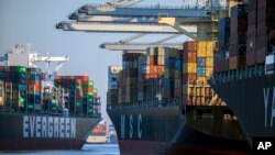 FILE - A container ship, left, moves past the Georgia Ports Authority's Port of Savannah, Sept. 29, 2021, in Savannah, Ga. The World Trade Organization is predicting a slowdown in the growth of global trade flows in 2023.