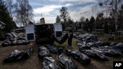 Cemetery workers unload bodies of killed civilians from a van in a cemetery in Bucha, on the outskirts of Kyiv, Ukraine, April 7, 2022.