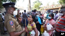Sri Lankans wait at a fuel station after spending hours in line to buy kerosene oil in Colombo, Sri Lanka, April 7, 2022. 