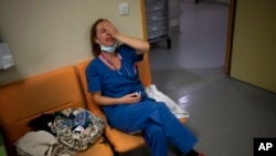 FILE - Nurse Marie-Laure Satta rests during her New Year's Eve shift in the COVID-19 intensive care unit at the la Timone hospital in Marseille, southern France, Dec. 31, 2021. France and Germany saw spikes in infections at that time and more hospitalizations because of the Omicron BA.2 variant.