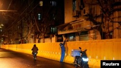 一名快递员在上海封城后给一户人家在围栏上递送食物。（2022年3月31日）