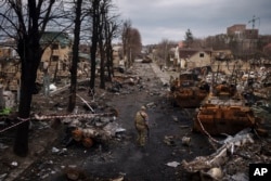 FILE - A Ukrainian serviceman walks amid destroyed Russian tanks in Bucha, on the outskirts of Kyiv, Ukraine, April 6, 2022.