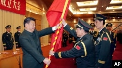 资料照：中共领导人习近平在北京举行的中国人民解放军战区成立大会上向火箭军将领、中国防长魏凤和（中）授予军旗。（2015年12月31日）