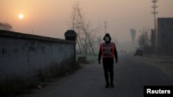 Artist Liu Bolin wearing a vest with 24 mobile phones walks in smog as he live broadcasts air pollution in the city on the fourth day after a red alert was issued for heavy air pollution in Beijing, China, Dec. 19, 2016. 