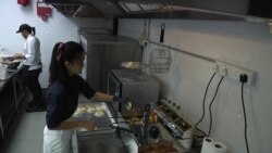 Teri and a part time kitchen worker make doughnuts. (Dave Grunebaum/VOA)