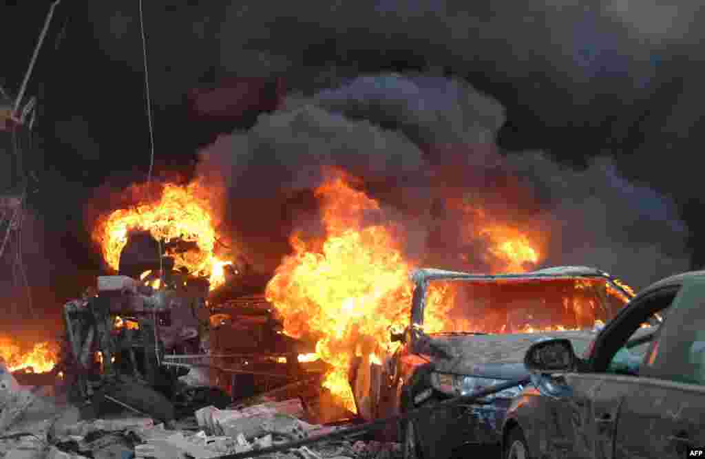 Flames engulf a vehicle following a car bomb along al-Khudary Street in the Karm al-Loz neighborhood in the central Syrian city of Homs.